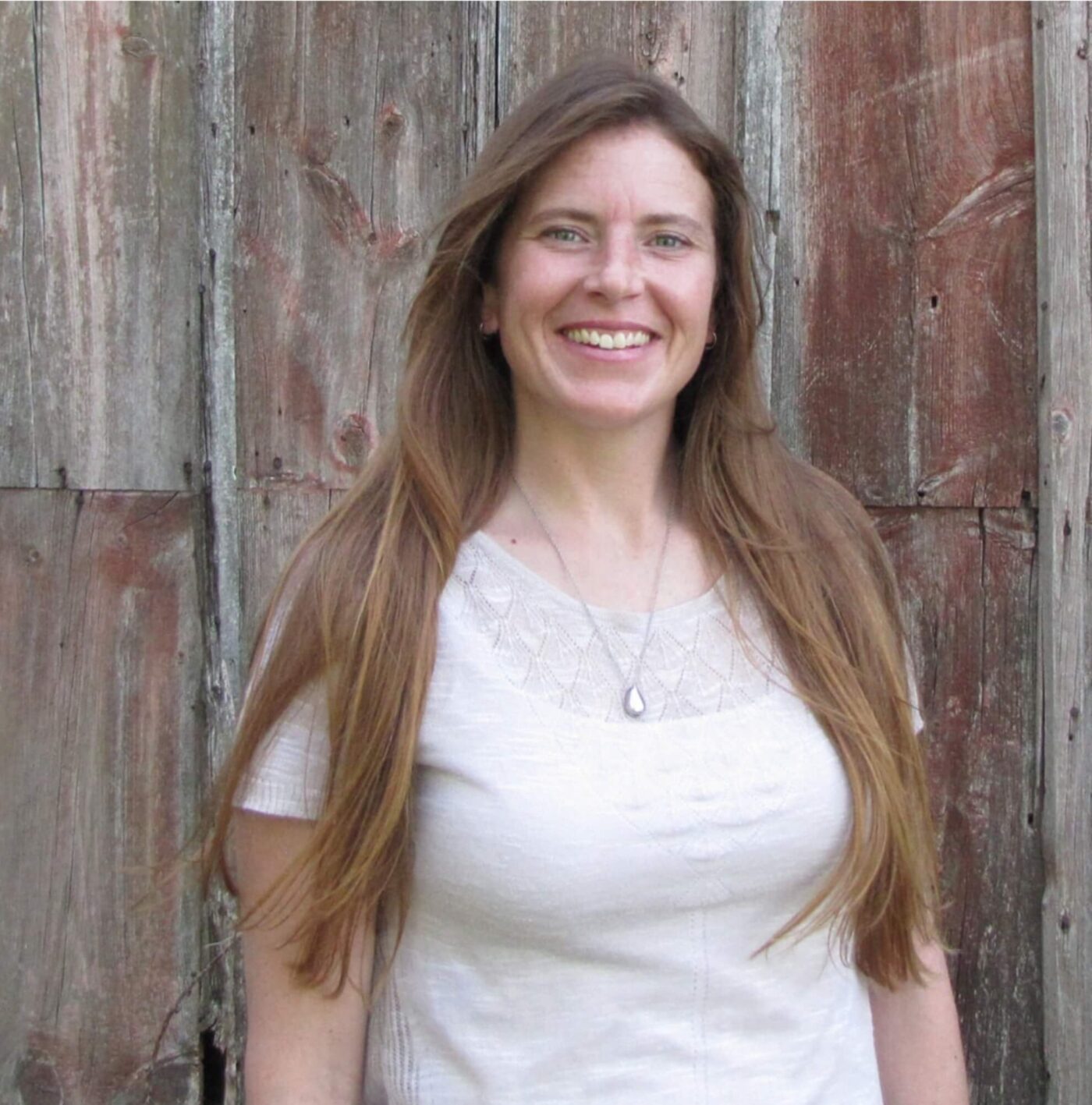 Caitlin Kempen, operations manager, smiling in front of a rustic wooden wall