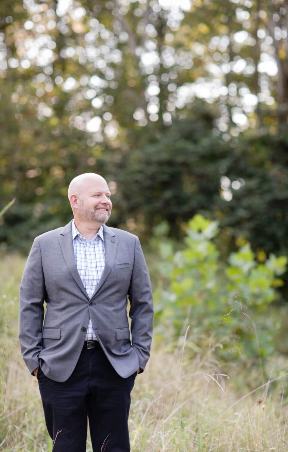 Financial planner Jim White standing in a field with trees in the background, smiling in a gray blazer