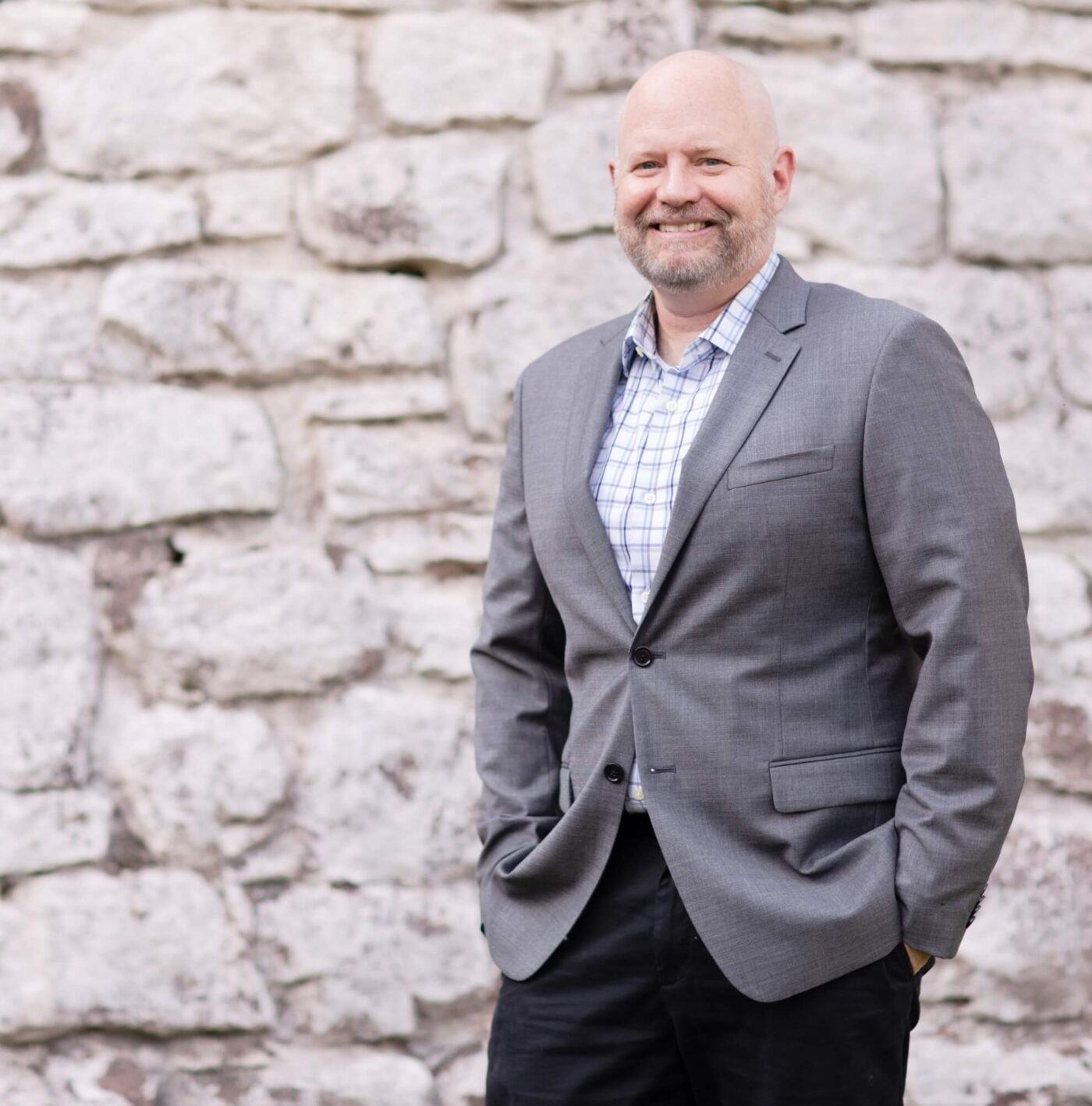 Jim White, financial planner, smiling in a gray suit in front of a stone wall