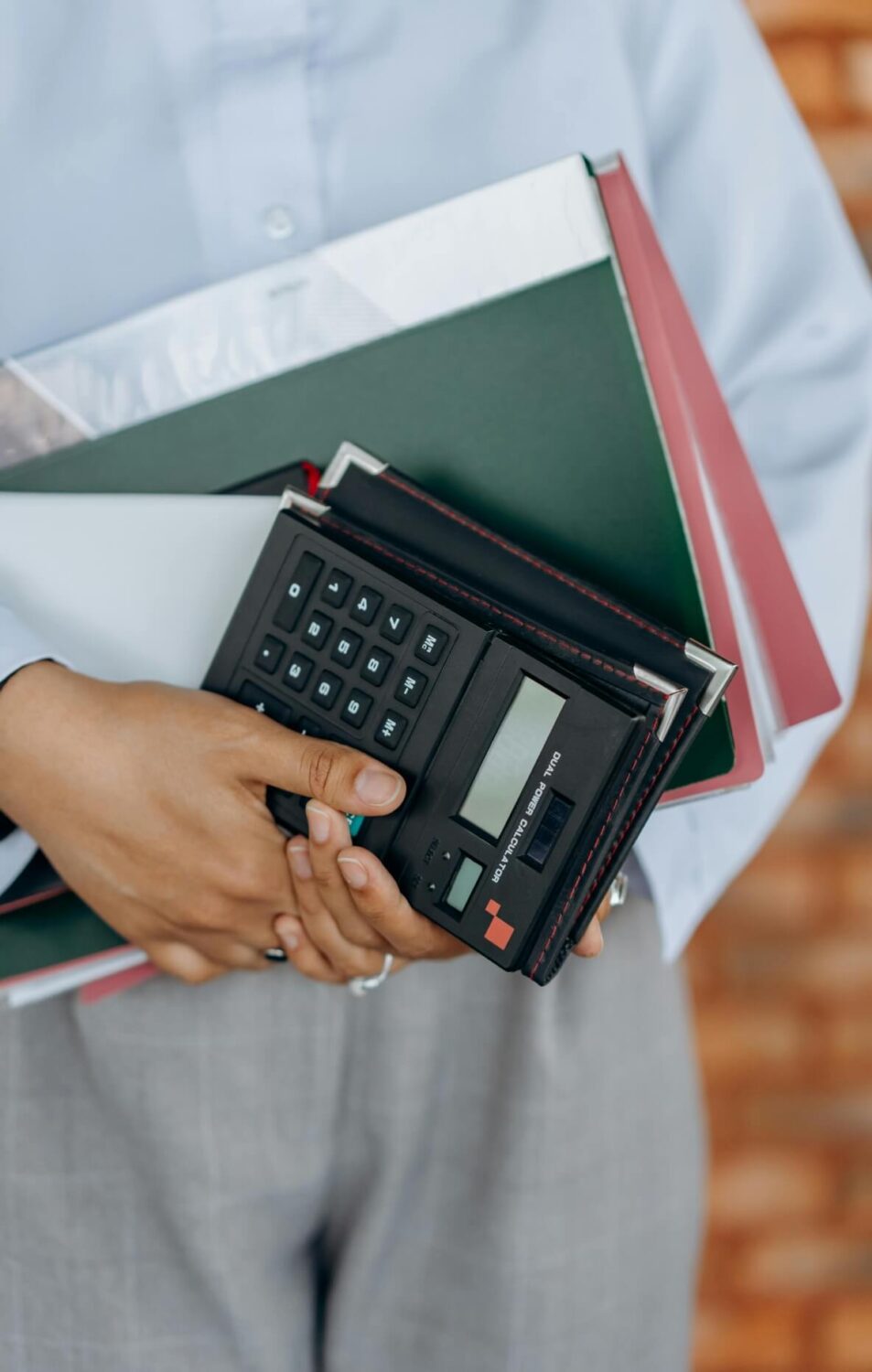 Person holding folders and a calculator, symbolizing financial planning or accounting