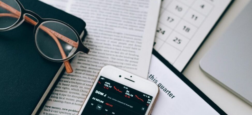 Flat lay of glasses, smartphone with stock market data, documents, and a calendar