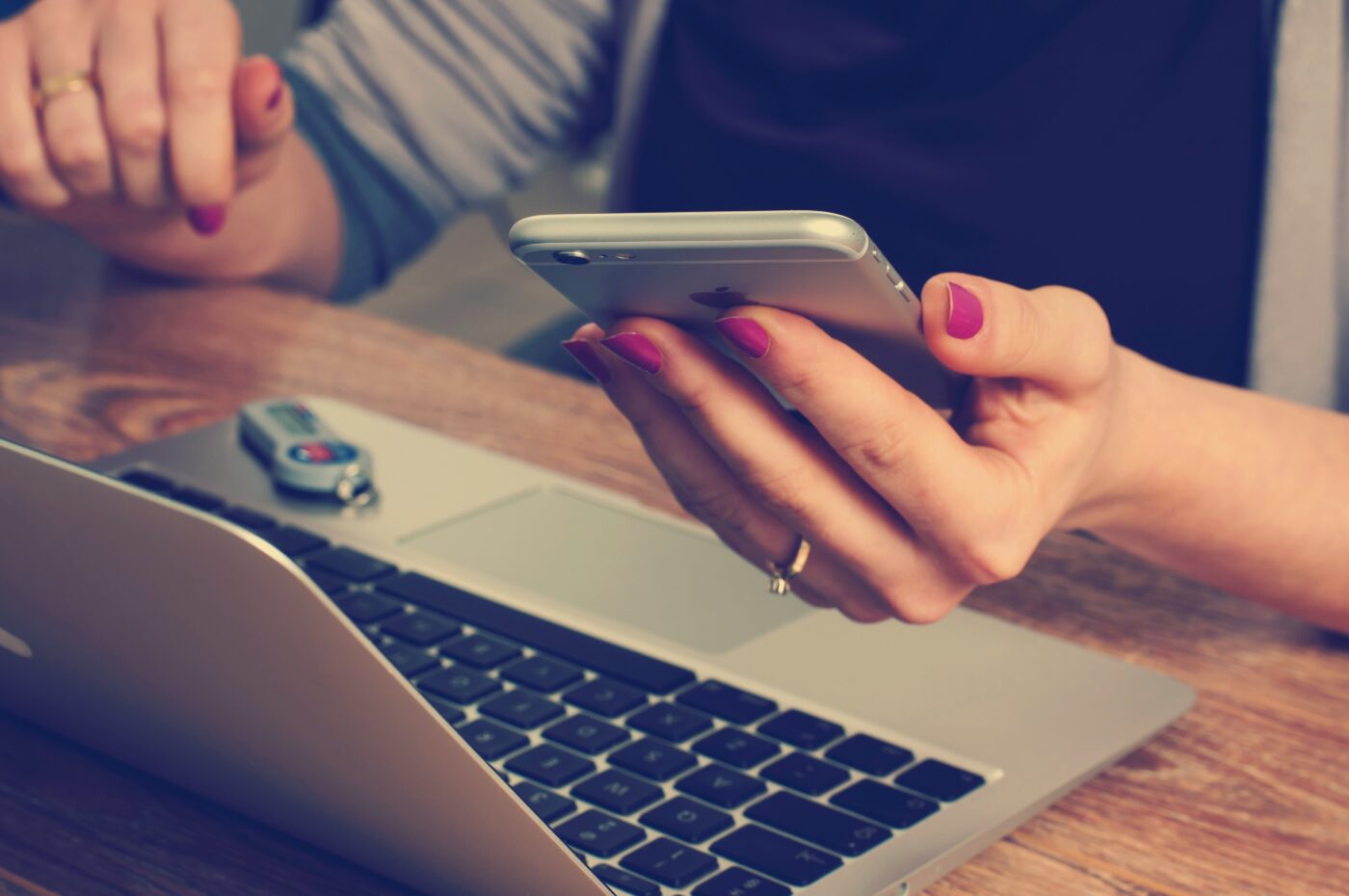 Person reviewing a suspicious message on a smartphone next to a laptop